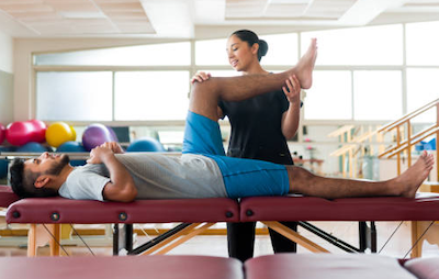 Physical therapist stretching a man's leg