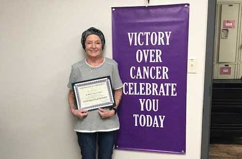 Sue Yocham next to "Victory Over Cancer" sign.