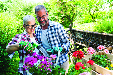 Mujer y hombre en un jardín regando una planta