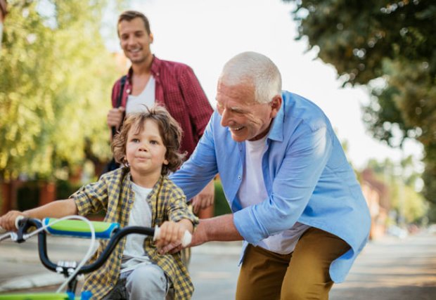 mature adult man with grandson riding tricycle