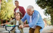 mature adult man with grandson riding tricycle