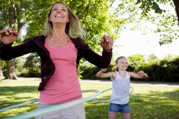 Young mom and her daughter smiling and hoola hooping