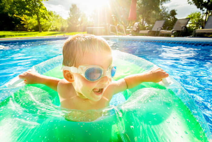 Child in bright sunshine enjoying pool time.