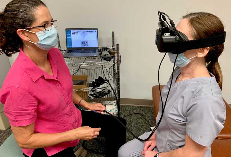 Healthcare staff person sitting, looking at patient with VR headset on